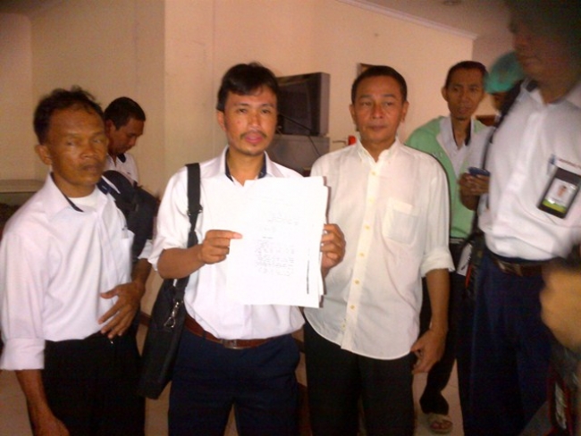Achmad karyawan PT ACS menunjukkan surat skorsing saat hendak hearing dengan Komisi II