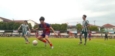 Winger Diklat Paku Jaya, Nurcholis (merah-biru) giring bola usai lepas dari hadangan pemain Putra FC Semanan, Jakarta Barat.