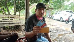 Warga desa Bakung Iwan saat menunjukkan KTP, ATM dan Buku Tabungan istrinya kepada detakbanten.com. (Iday).