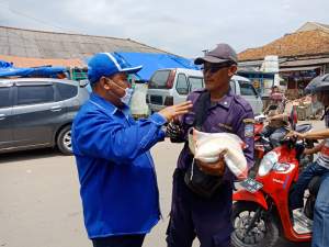 Ketua Fraksi Partai Demokrat Kabupaten Serang Riky Suhendra saat menbagikan beras kepada tukang parkir