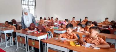 Siswi belajar dengan gedung sekolah yang baru