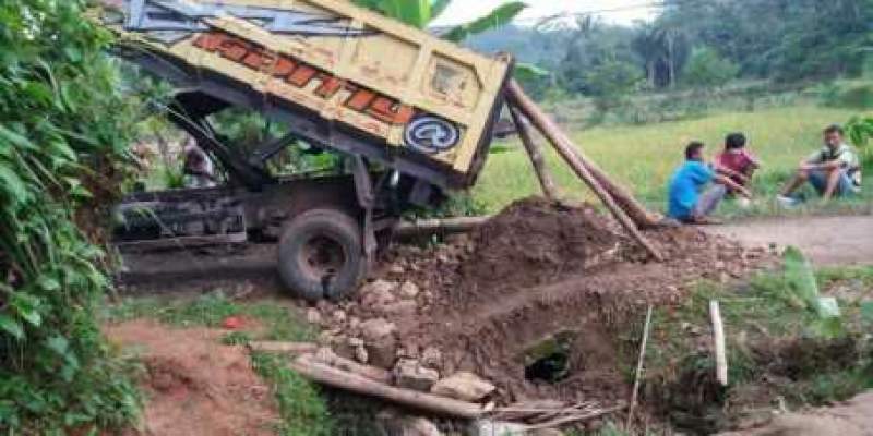 Truk mengangkut material terperosok ketika melewati Jembatan yang amblas di Kampung Babakan Waru, Desa Cisimeut Raya.